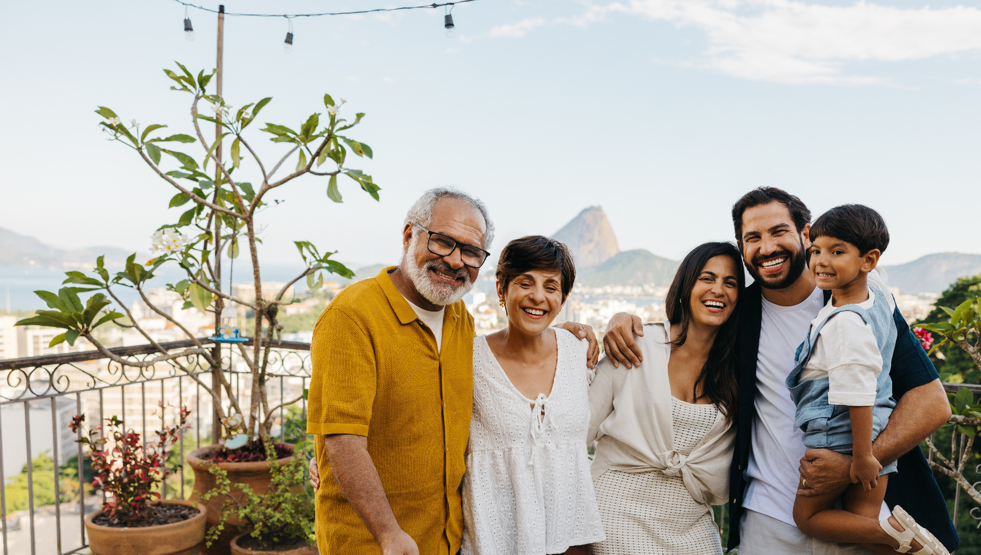 Família sorrindo em varanda com vista para o Rio de Janeiro